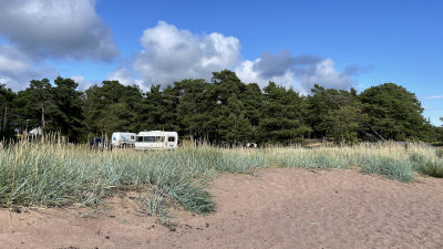 Bild av husbilar som är parkerade på en sandstrand.
