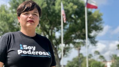 Lucy Caballos-Felix står framför USA:s och Texas flaggor.