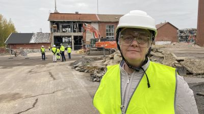 Kvinna i reflexväst och skyddshjälm.