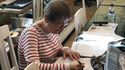 Beatrice Wallman sitter vid ett bord och skriver.