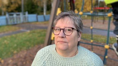 Kvinna i ljusgrön tröja framför klätterställning på dagisgård.