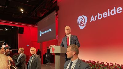 Jonas Gahr Störe uppe på scen. I förgrunden vakter.