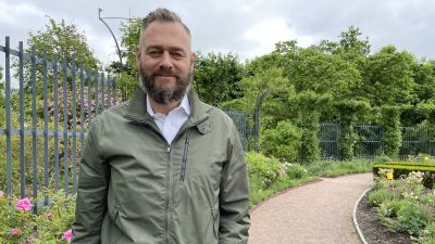Olof Lundh ser in i kameran med ett blomhav bakom sig.