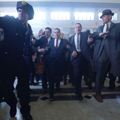 Frank Sheeran (Robert de Niro) eskorterar Jimmy Hoffa (Al Pacino) till domstolen, de är omringande av poliser och män.