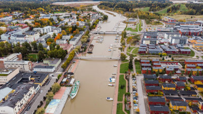 Flygbild över en å som flyter genom höstlig stad