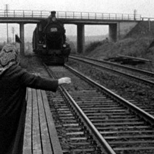 Nainen heilauttaa kättään junalle