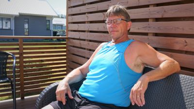 Man i blå ärmlös t-skjorta sitter på en terass.