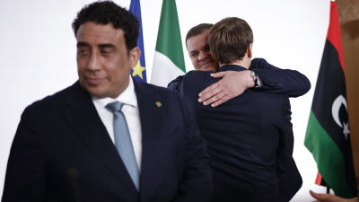 Frankrikes president Emmanuel Macron kramar om Libyens premiärminister Abdul Hamid Dbeibah med presidentrådets ordförande  Mohamed al-Manfi i förgrunden.
