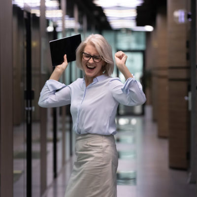 Kvinna dansar och gör seger-gester i kontorsmiljö