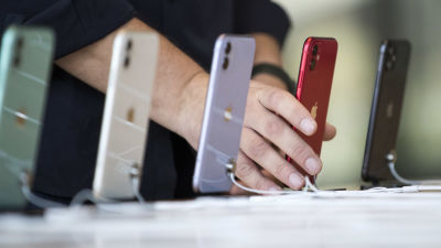 Fem Iphone 11-telefoner i olika färger på rad i ett köpcentrum i Dubai. En person håller i telefonen som är röd. Telefonerna är fotade så att bara baksidan med Apple-logon syns.