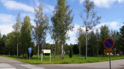 Korsning mellan väg och gång- och cykelväg. I bakgrunden gräsplan med träd.