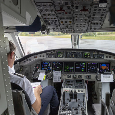 En person sitter i förarens plats i ett flygplan.