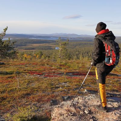 Retkeilijä Muonion Äkäskerolla, Ylläs-Pallastunturin kansallispuistossa maaruskan värittämässä maisemassa.