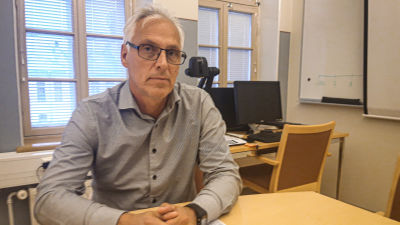 Jan Levander sitter vid ett skrivbord och tittar in i kameran med allvarlig min.