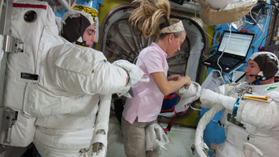 Astronautit Chris Cassidy, Karen Nyberg ja Luca Parmitano valmistautumassa avaruuskävelyyn avaruusasemalla. Cassidy ja Parmitano ovat pukeutuneet avaruuspukuihin, Nyberg auttaa heitä kuvassa keskellä ja on itse siviilivaatteissa.