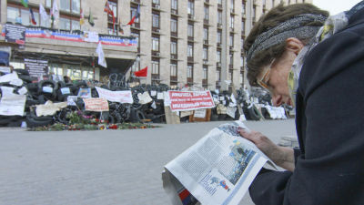 Kvinna läser en tidning utanför en myndighetsbyggnad i Donetsk i Ukraina.