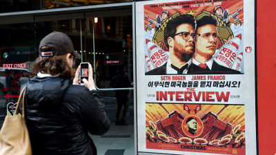Kvinna fotograferar reklamaffisch för The Interview utanför Regal Theater i New York den 18 december 2014.