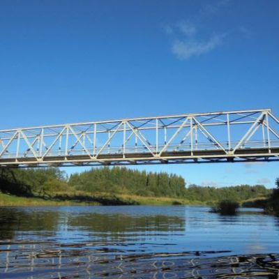 Joen yli kulkeva silta kuvattuna auringonpaisteessa.