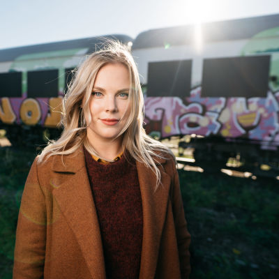 En kvinna i ljust hår står framför ett tåg