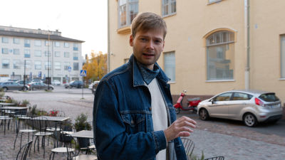 En ung man står och förklarar något mot kameran och viftar med handen.
