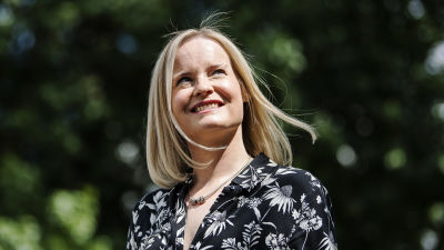Riikka Purra ler och tittar åt sidan uppåt.