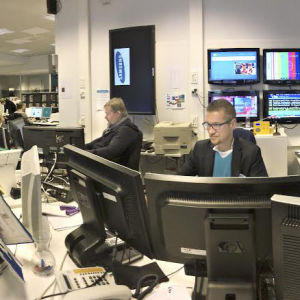 Ylen uutishuone  ja kuvassa toimittajia istumassa työpisteissään