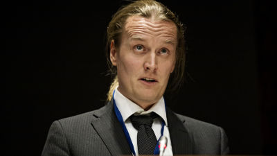 Johan Strang i slips, med rynkad panna, i talarstol.