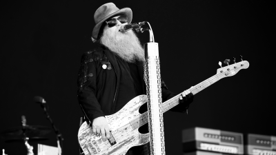 Rockbandet ZZ Tops basist Dusty Hill står på en scen och sjunger i en mikrofon. Bilden är tagen på en festival 2019.