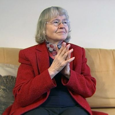 Liisa Kauppinen istumassa sohvalla.