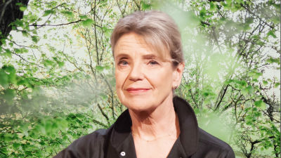 Stina Ekblad småler in i kameran. Bakgrunden är en grön skogsdunge.