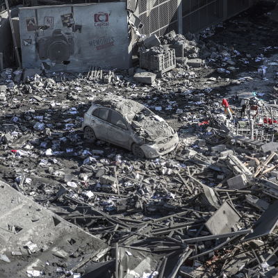 En bil mitt bland bråtet efter en sönderbombad byggnad i Gaza City på söndag morgon.  