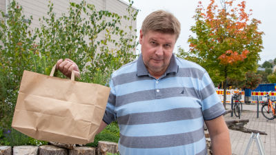 Seppo Elisanen håller upp en papperspåse med gran- och tallplantor i.