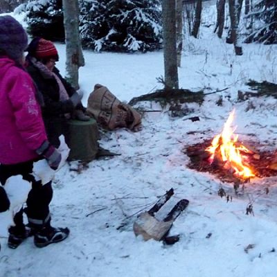 Kuvassa tonttuleiriläiset nuotiolla tontun kanssa.