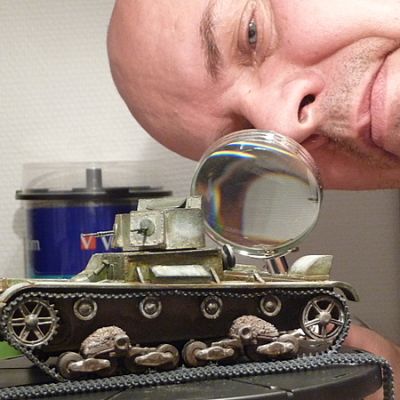 Ari Alanen katsoo panssarivaunun pienoismallia suurennuslasin läpi.