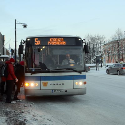 Ihmisiä nousemassa bussiin torin laidalla Kuopiossa.