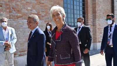 Europeiska centralbankens chef Christine Lagarde ler, omgiven av män i kostym.