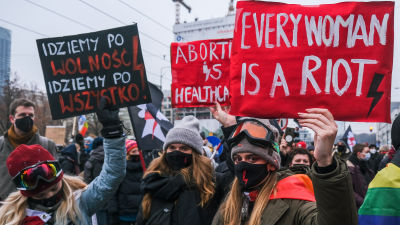 Människor demonstrerar för rätten till abort i Polen. Människor i munskydd håller i skyltar.