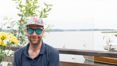 En man med solglasögon vid en hamn.