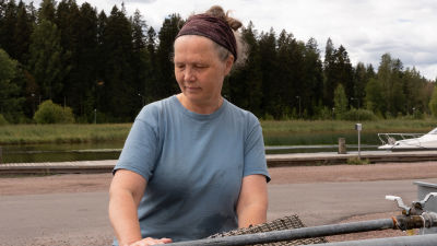 Kvinna vid mattvättnignsställe med en å i bakgrunden.