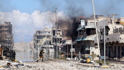 Soldat springer över gatan under strider om staden Sirte år 2011 då inbördeskriget i Libyen bröt ut. 