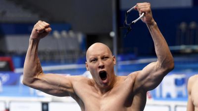 Kalju mies tuulettaa uimalasit kädessä uima-altaan edessä