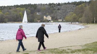 Människor promenerade längs en strand i Sätra, i sydöstra Stockholm den 25 april.