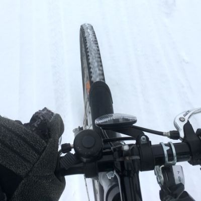 Ihminen pyöräilee pitäen yhdellä kädellä kiinni ohjaustangosta.