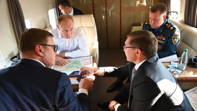 Vladimir Putin sitter i ett privatplan med katastrofminister Jevgeni Zinitjev och andra ministrar.