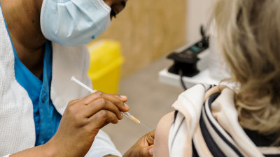 Sjukskötare vaccinerar en äldre patient.