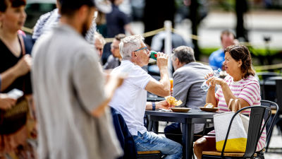 Två personer sitter vid ett bord och äter på en uteservering.