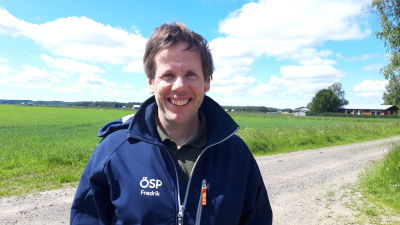 man ler mot kameran ute på gård