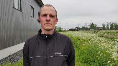 Man står med armarna bakom ryggen och ser in i kameran.