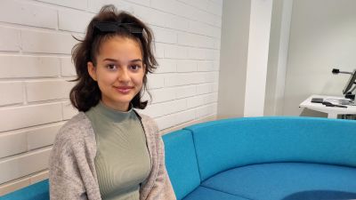 Tonårsflicka sitter på en soffa och ser mot kameran.