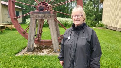 Kvinna står och ler mot kameran. Hon bär en svart jacka och glasögon.